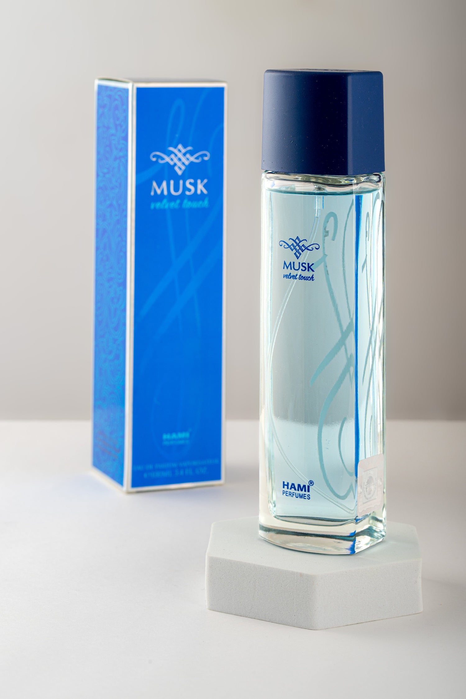 Musk cologne bottle and packaging on a white surface with a light gray background