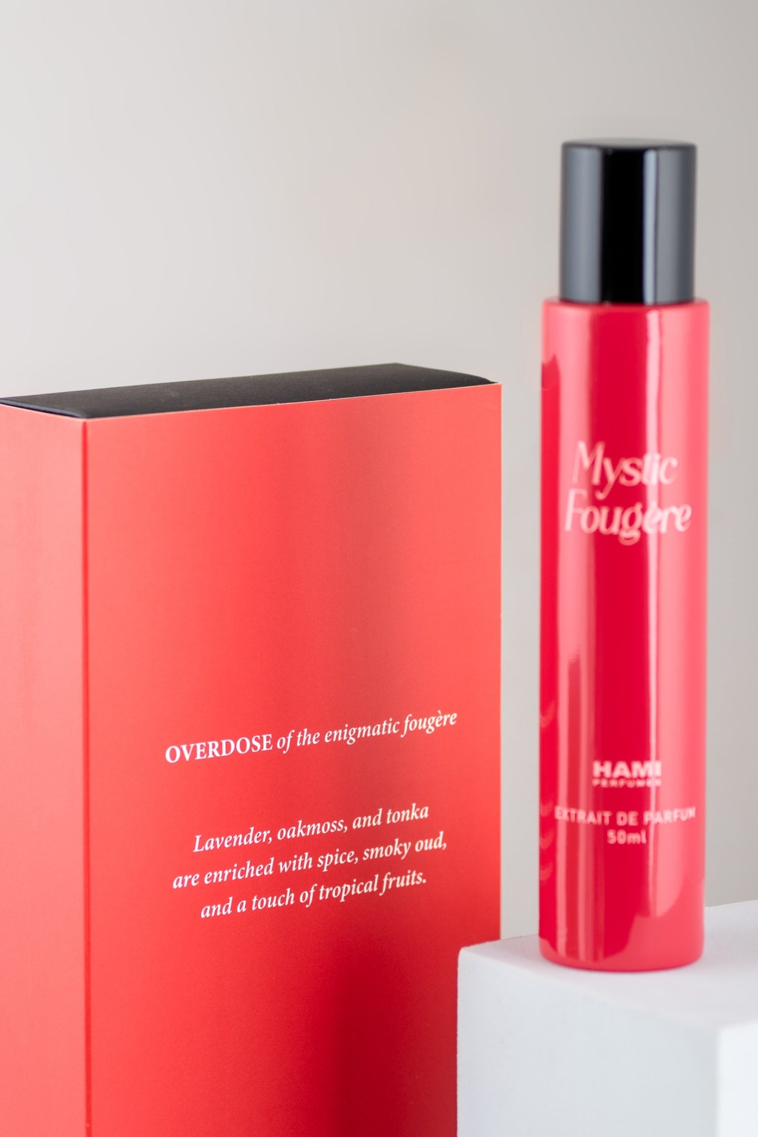 Red perfume bottle and packaging with 'Mystic Fougère' branding on a light gray background