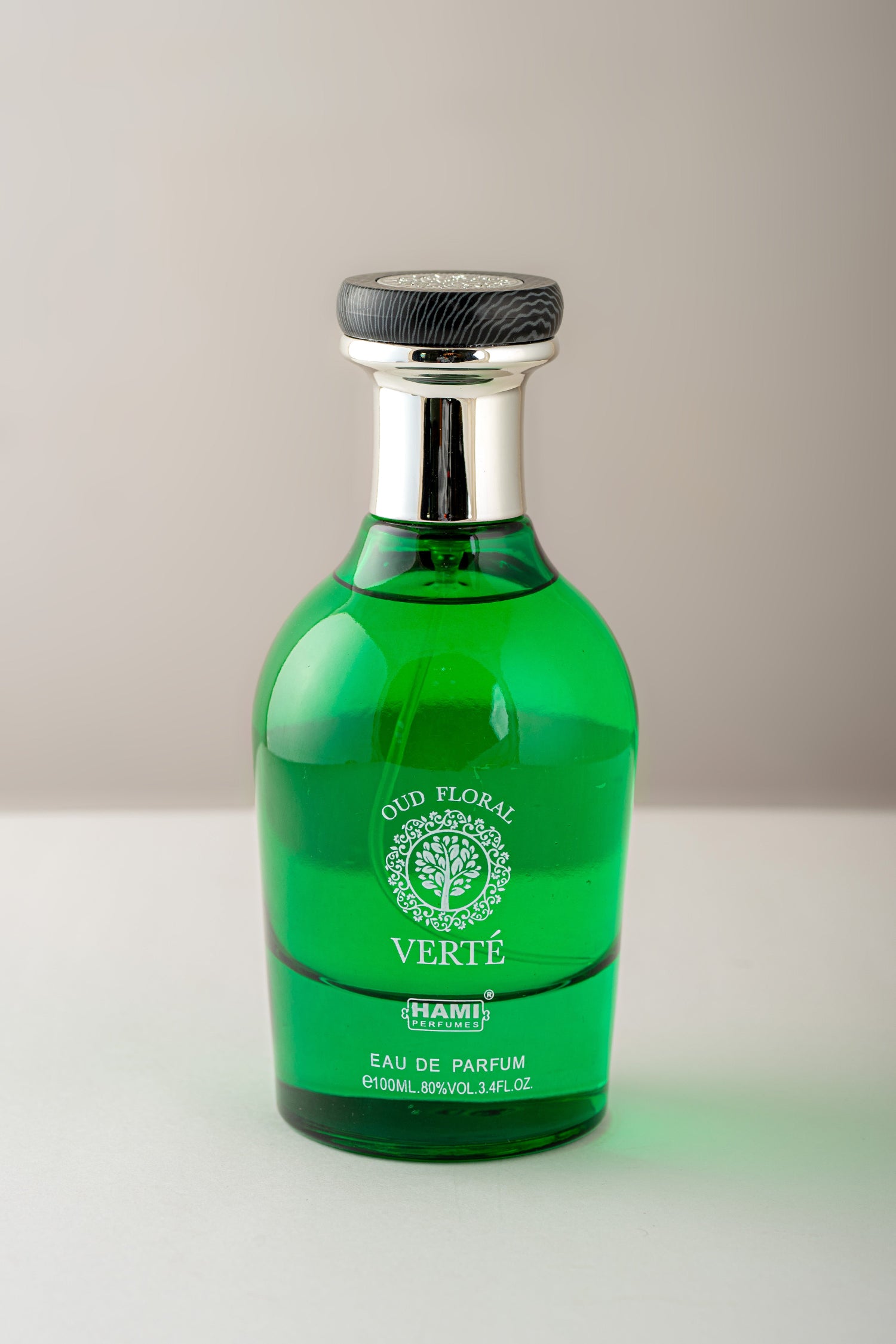 Green perfume bottle with silver cap on a light gray background